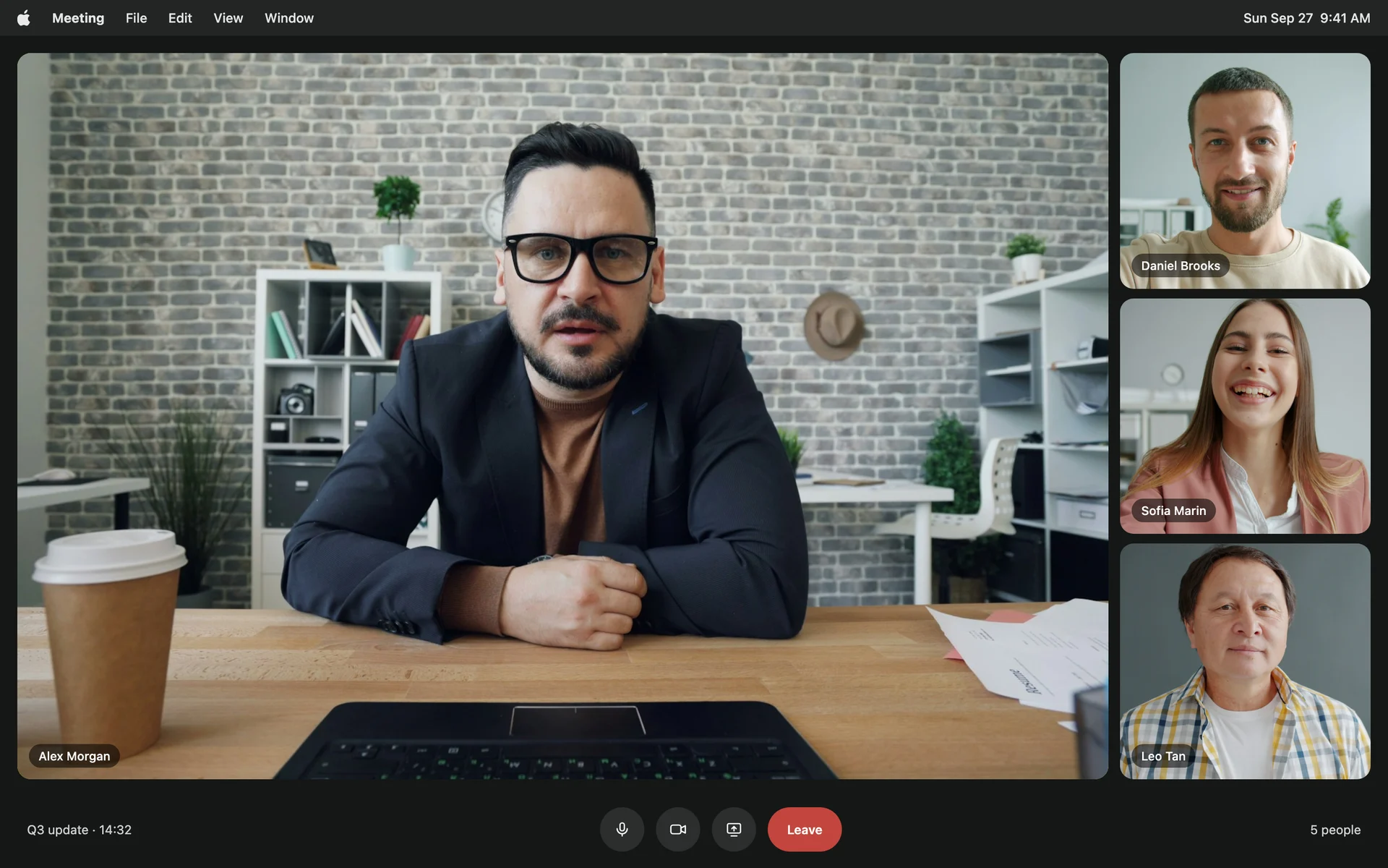 A video call on a Mac, with the main speaker looking straight into the camera and three other participants in tiles beside him