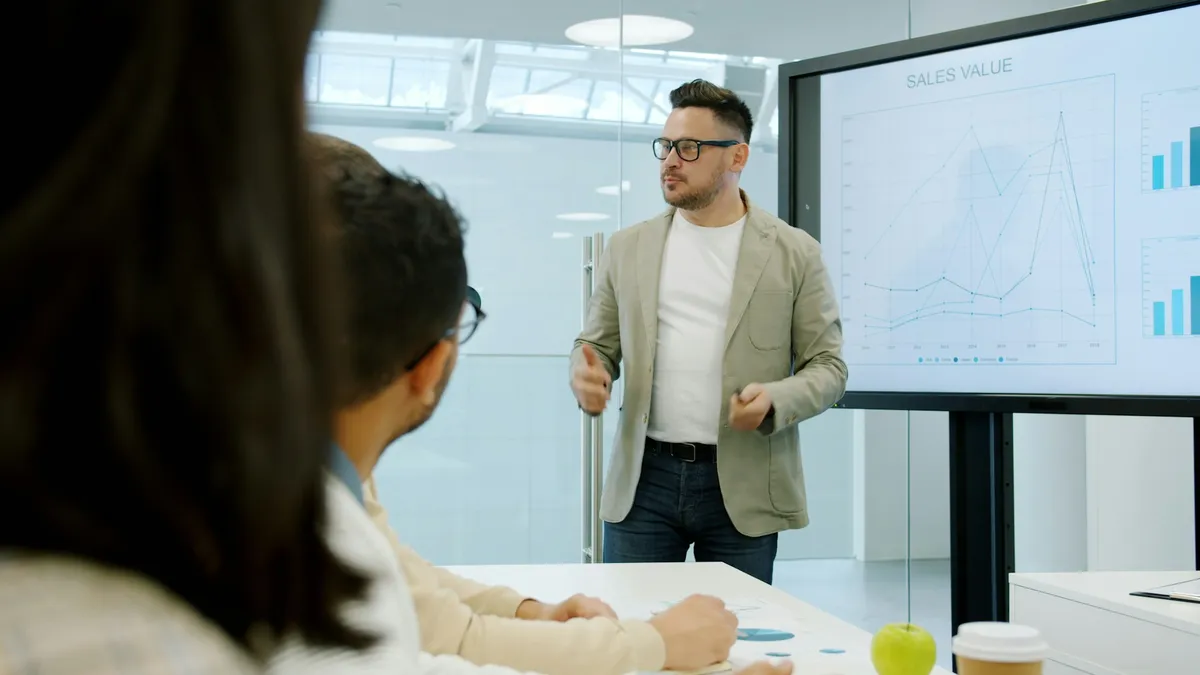 A man presenting to colleagues in front of a screen